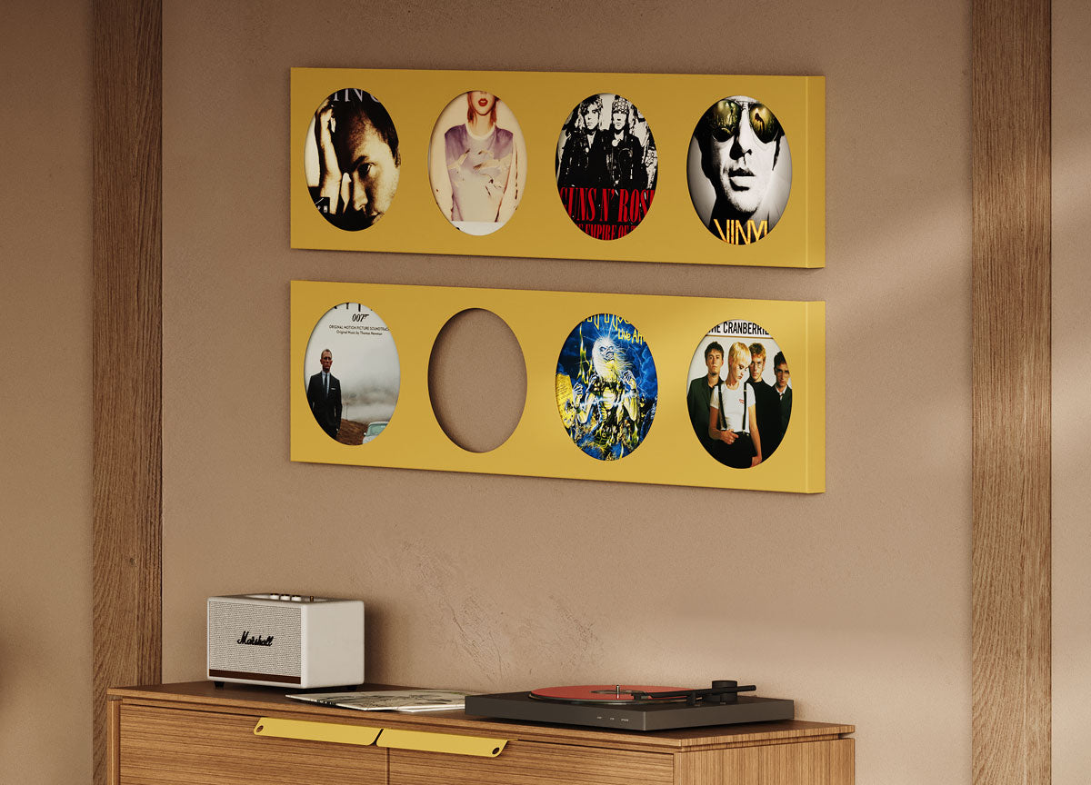 Two yellow wall-mounted display ledges hold oval photo frames with musical artists above a wooden cabinet with a turntable and speaker against a beige wall.