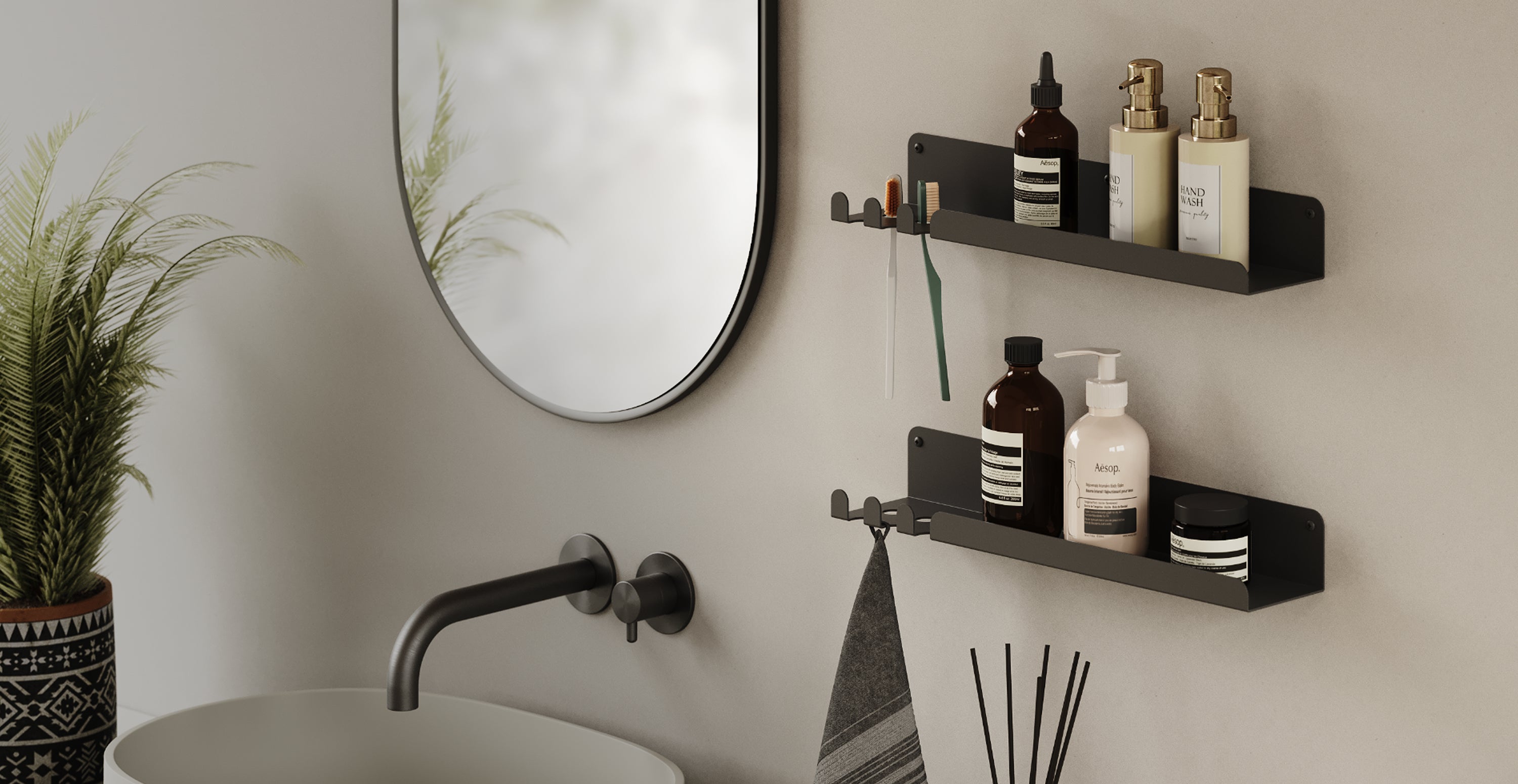 Two black metal wall shelves with bath products and a towel hanging below near a round mirror and sink basin