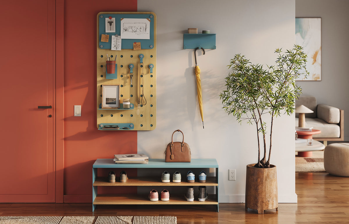 Warm modern interior with a wall mounted pegboard organizer, small display shelf, low wood console, and potted tree beside a seating area