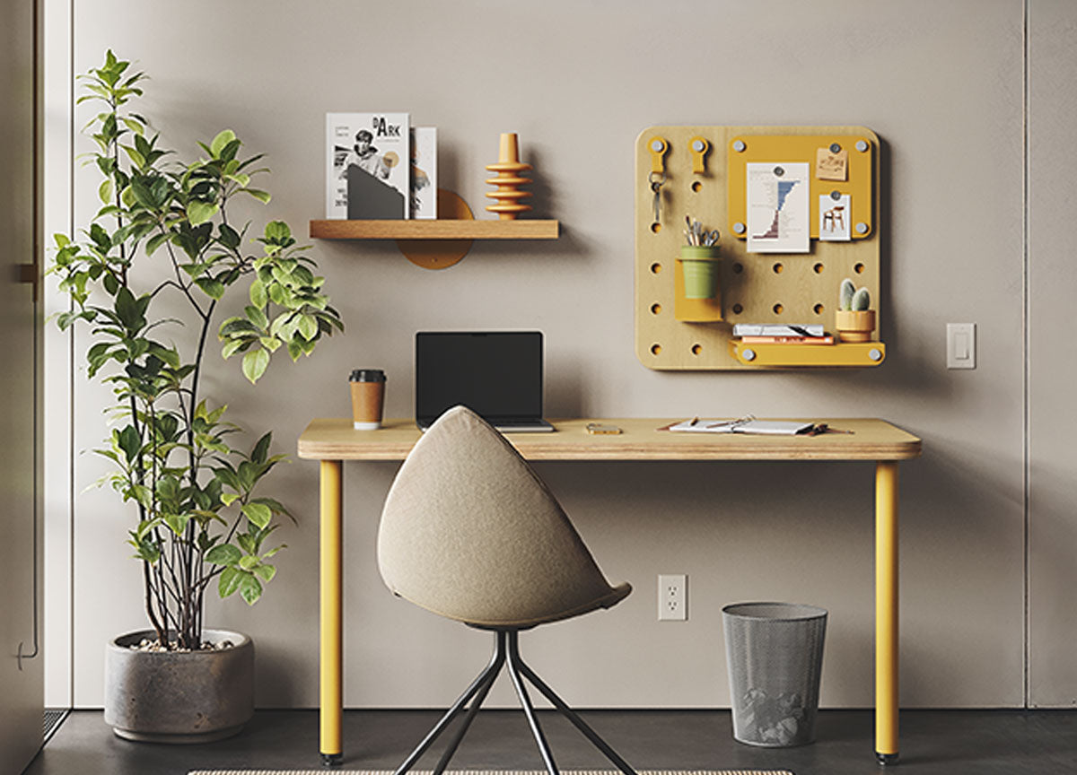 Minimalist home office with a wood desk yellow legs a black chair wall shelf pegboard and potted plant