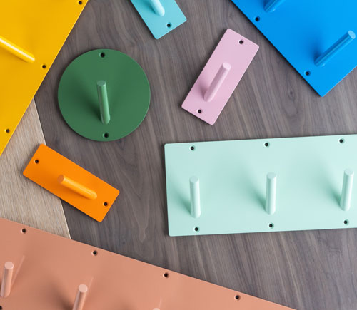Assorted colorful wall hooks and hangers in various shapes and sizes arranged on a wooden surface, showcasing minimalist design.