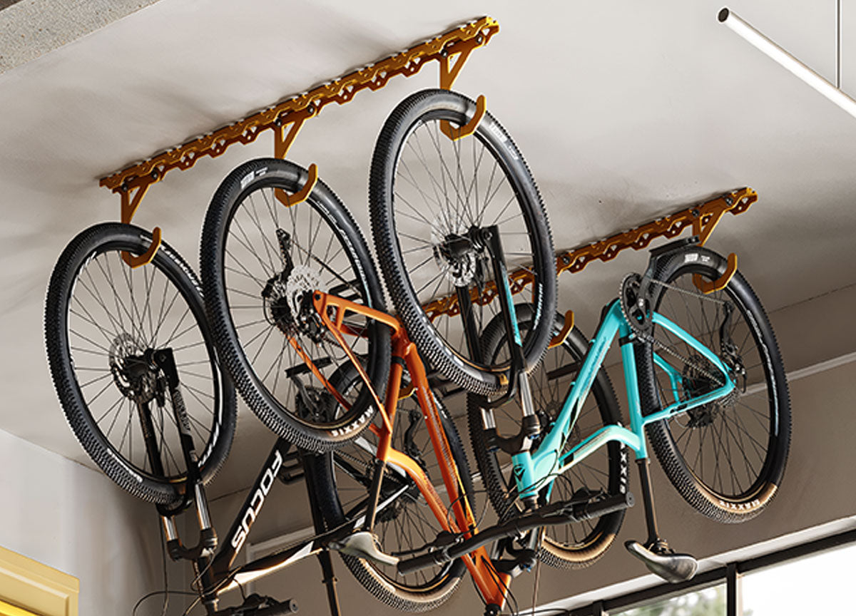 Several bicycles suspended from ceiling mounted racks in a garage or storage area