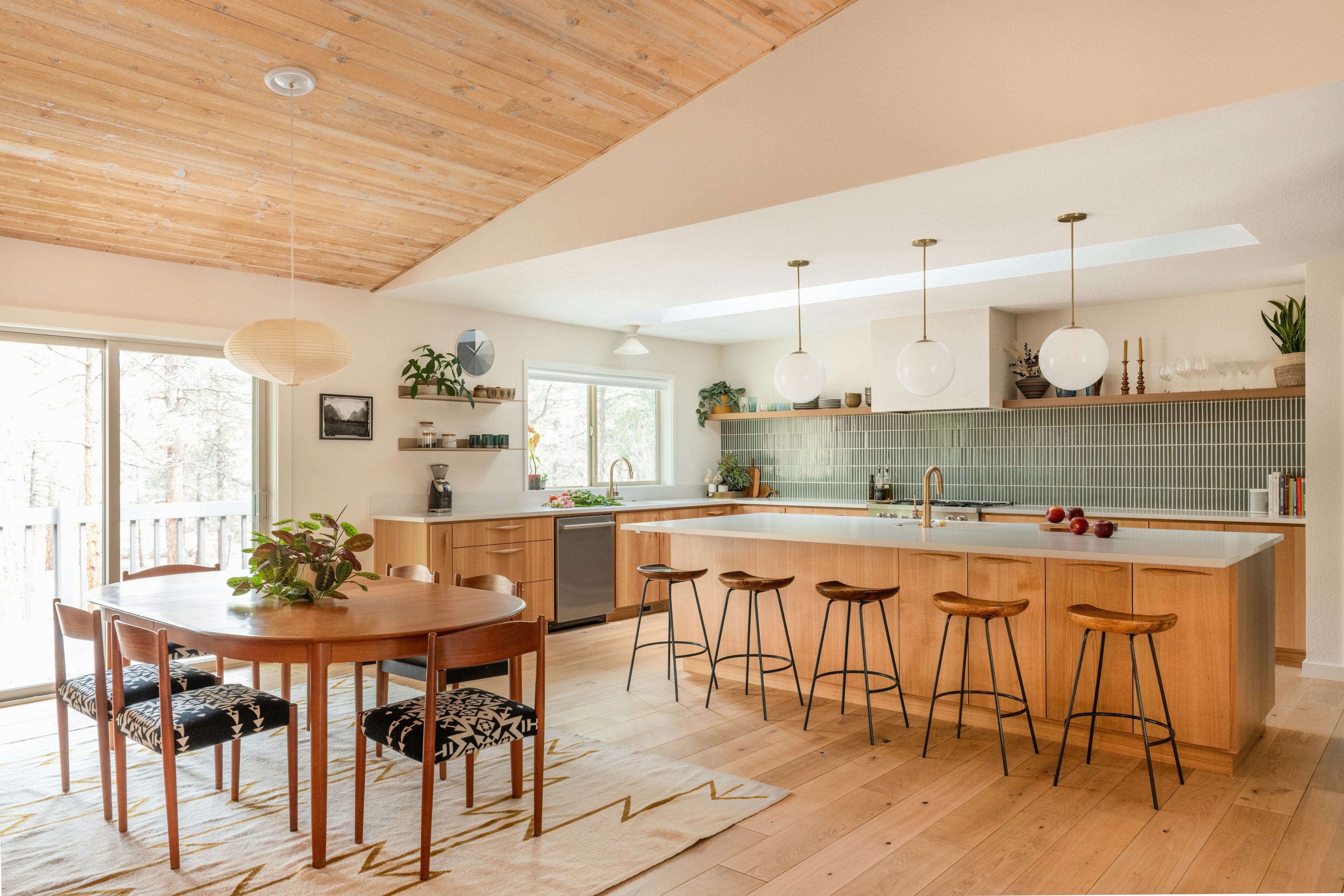 Aksel floating shelves in a mid-century inspired kitchen with globe pendants, wood island seating, and green tiled backsplash.