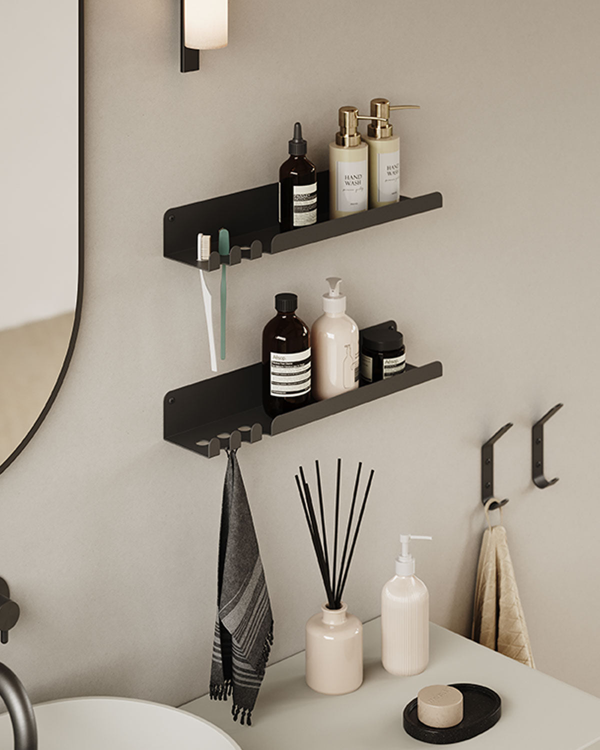Two black wall shelves hold bathroom bottles above hooks with a hanging towel, robes, soap, and reed diffuser near a sink