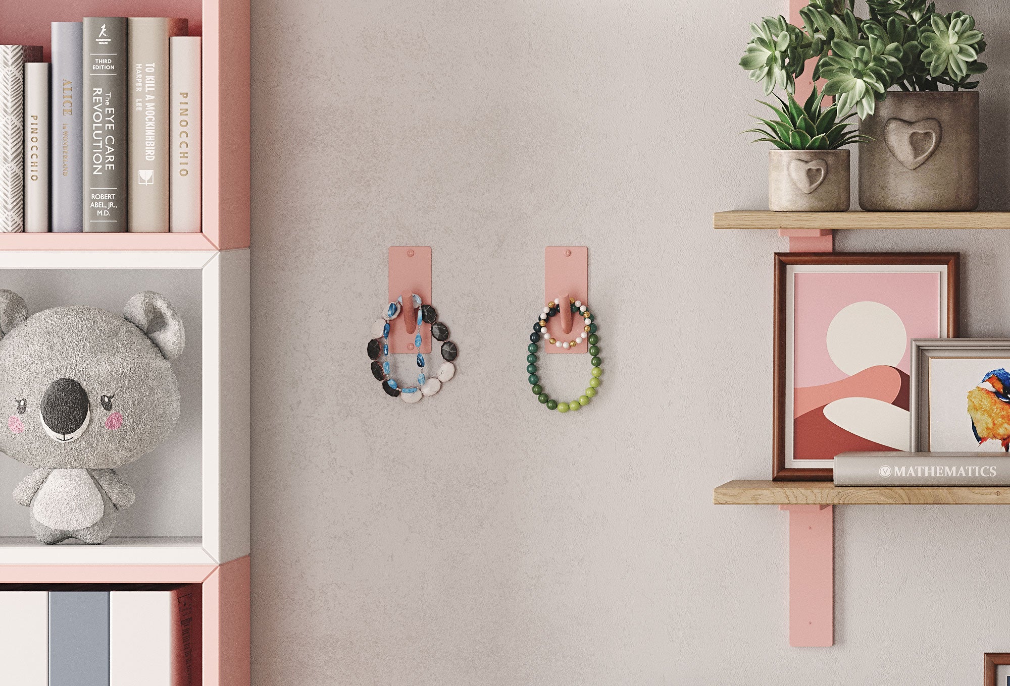 Two pink wall hooks holding beaded bracelets mounted between a white bookshelf with books and a gray stuffed koala and floating wood shelves displaying potted plants and framed artwork.