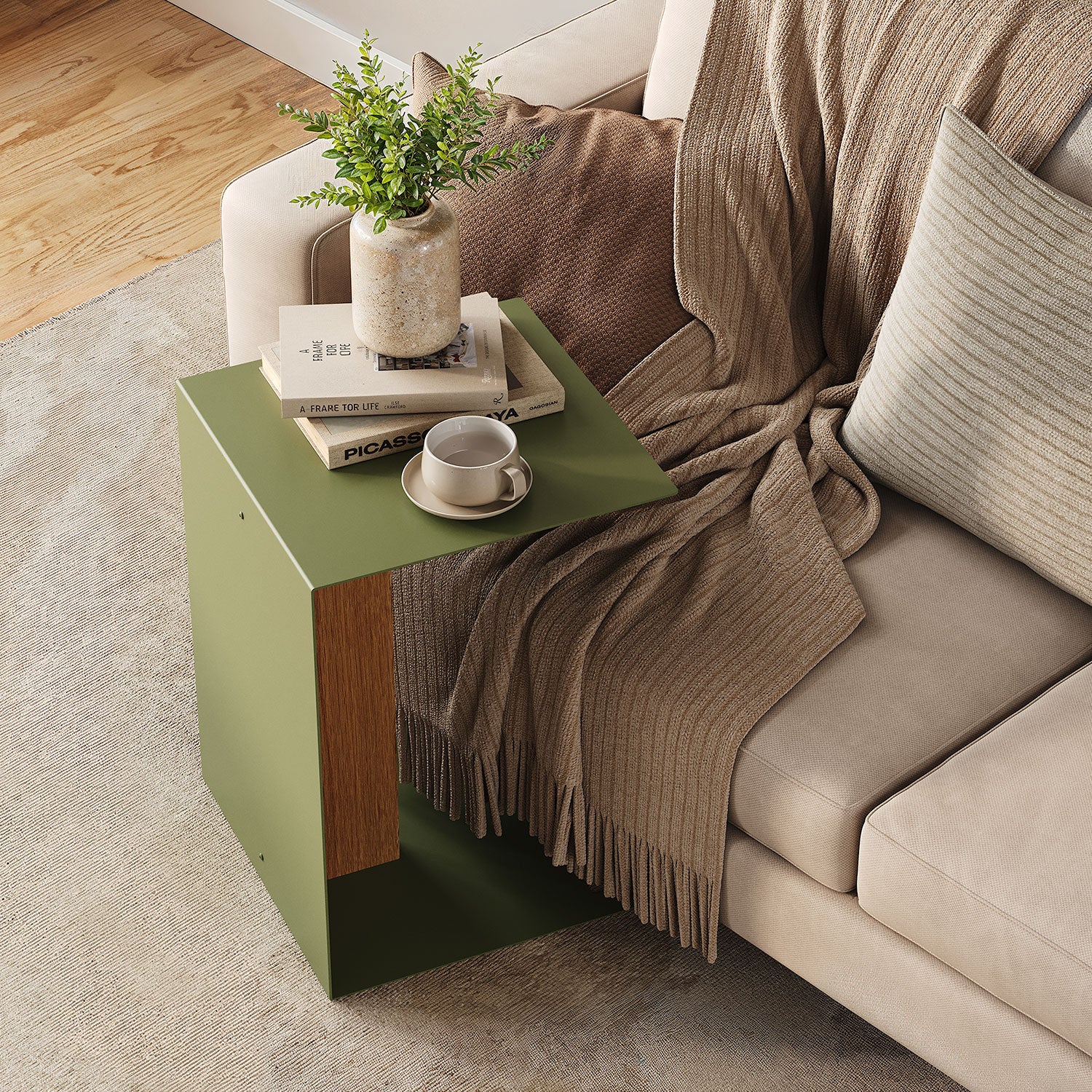 Baxter Side Table in olive green with a wood accent beside a sofa styled with books a plant and coffee cup