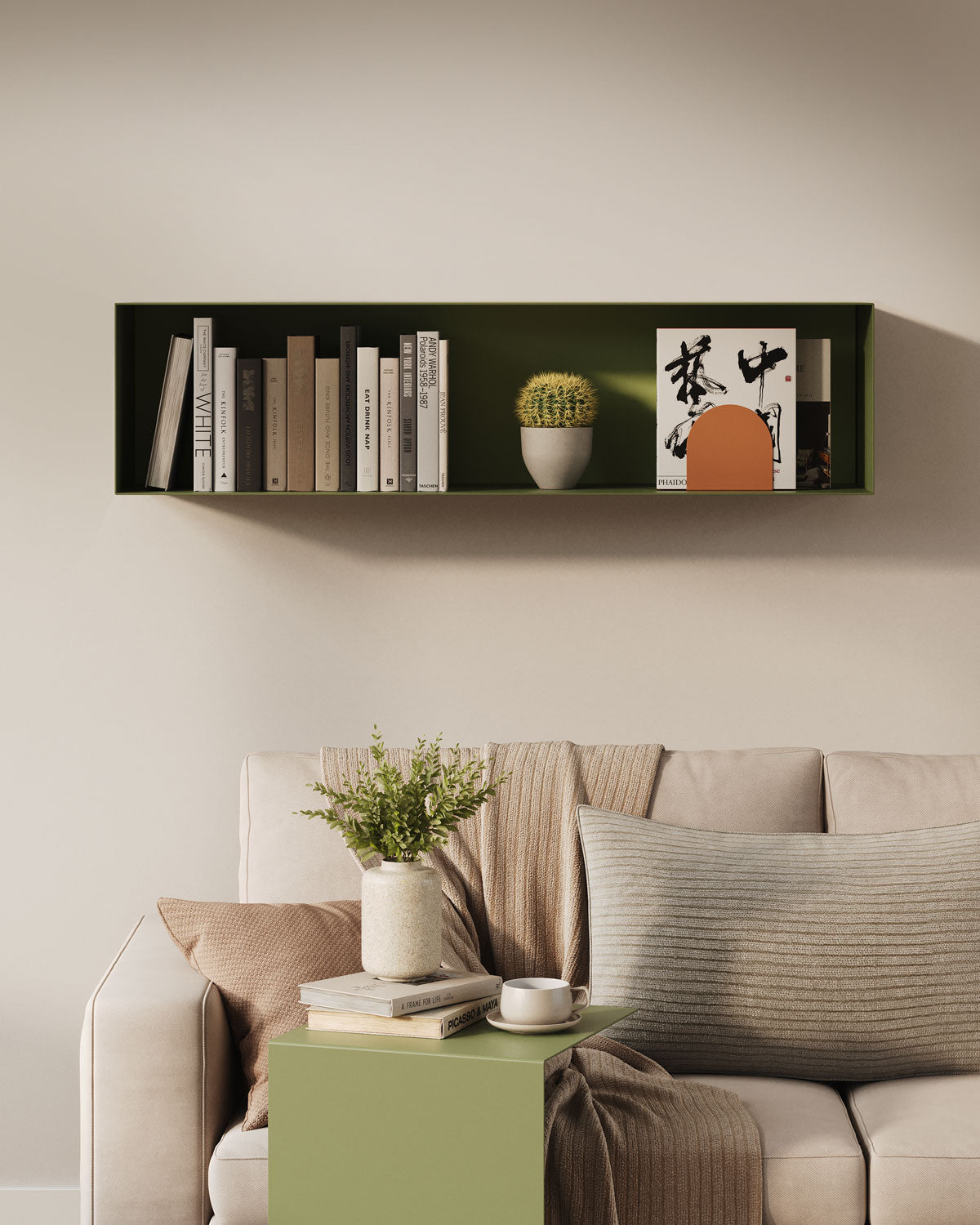 Warm minimalist living room with a deep green wall shelf displaying books art and a cactus above a neutral sofa and side table