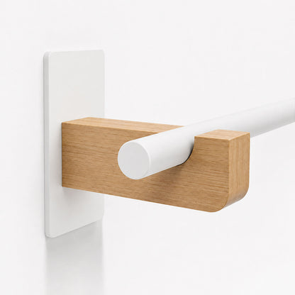 Close-up of minimalist wall-mounted Draper Curtain Rod System featuring a white rod held by a solid hardwood and steel bracket.