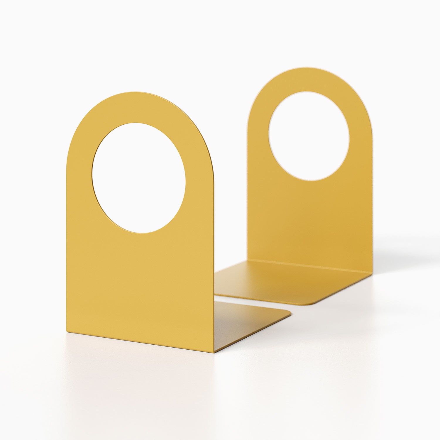 Geo Round Open Bookend (Set of Two) in mustard yellow metal with minimalist round cutout design for functional shelf and wall display organization.