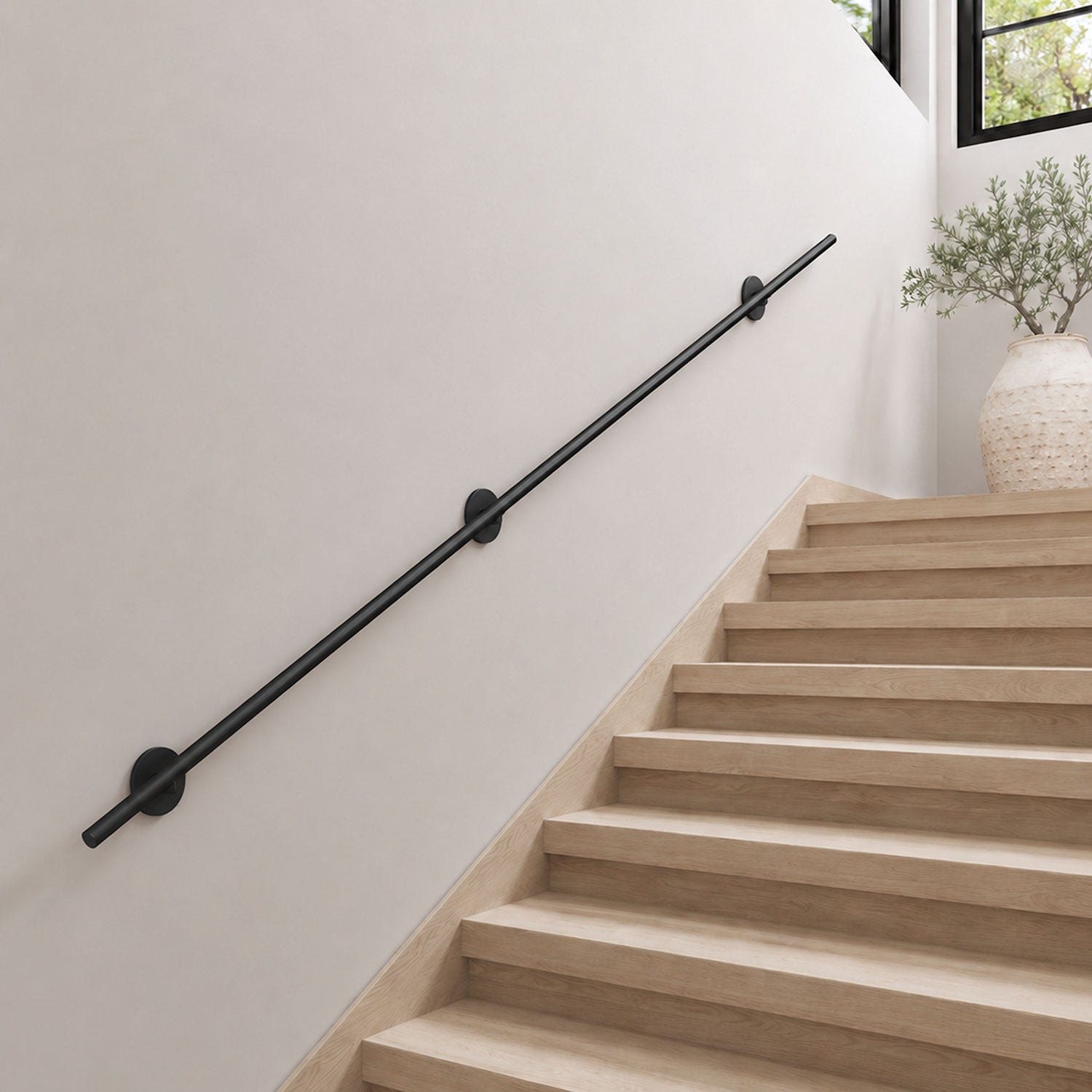 Grip Stair Rail in matte black metal, installed along minimalist staircase wall for functional support and safety.