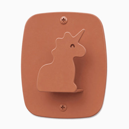 Minimalist ceramic wall hook shaped like a unicorn in terracotta color, designed for organizing kids’ rooms with Kiddo Hooks.