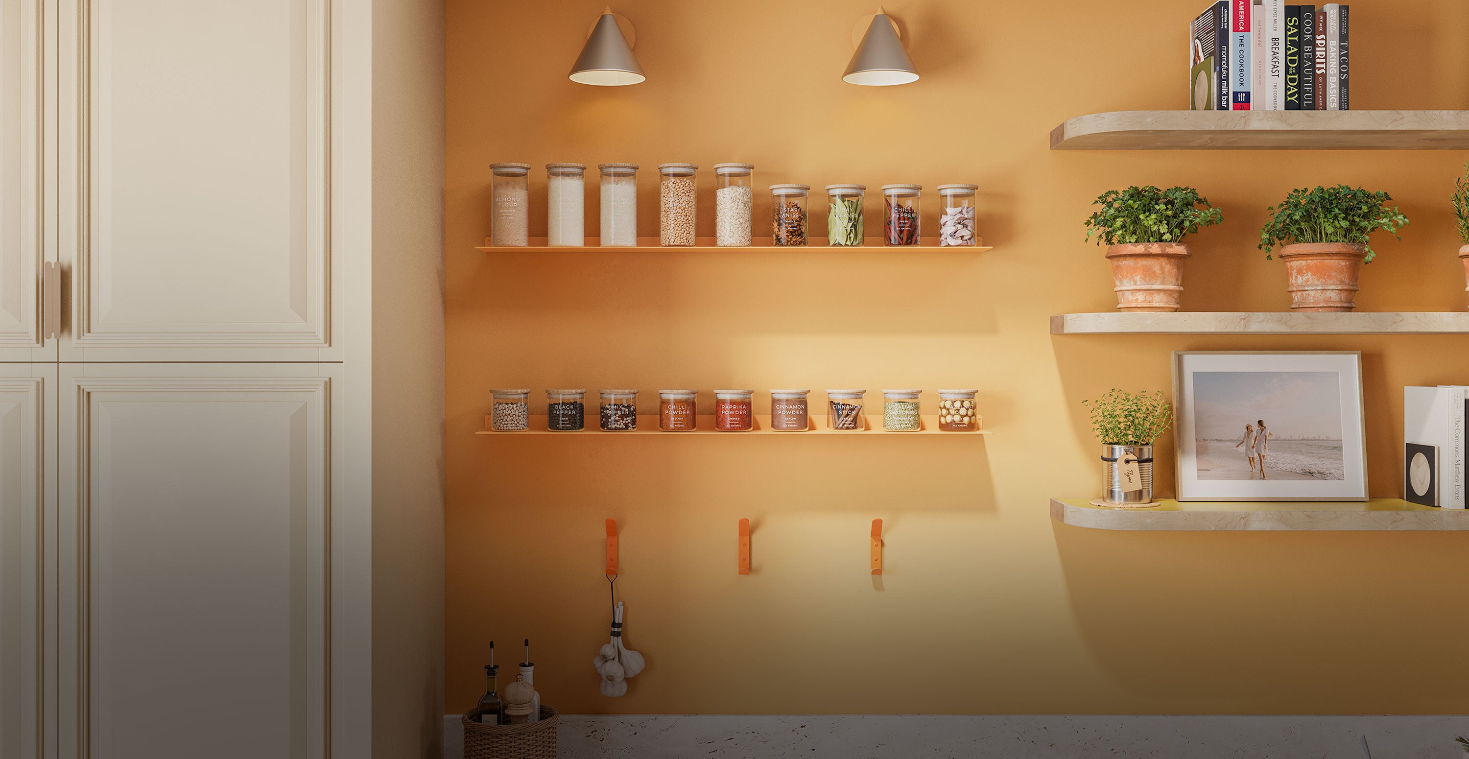 Minimalist kitchen wall with floating shelves holding glass jars, potted plants, books, and framed photo, featuring warm orange paint and white cabinetry.