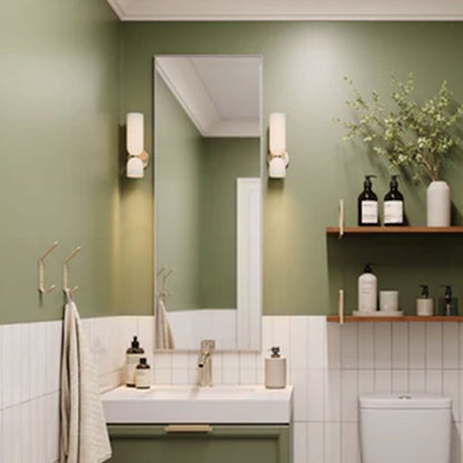 Modern bathroom with green walls, white tiled lower half, rectangular mirror, wall sconces, and Lars Floating Vanity Wall Mount Bracket supporting wooden shelves with toiletries and decor.