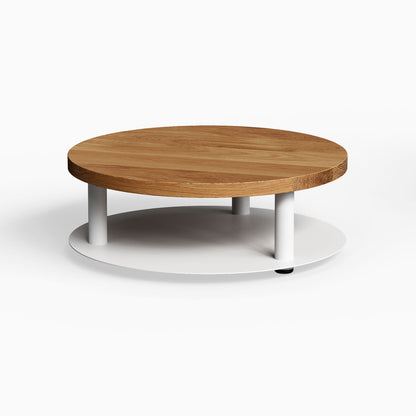 Ledger Coffee Table with a round solid hardwood top and white metal base, combining minimalist design and functional storage.