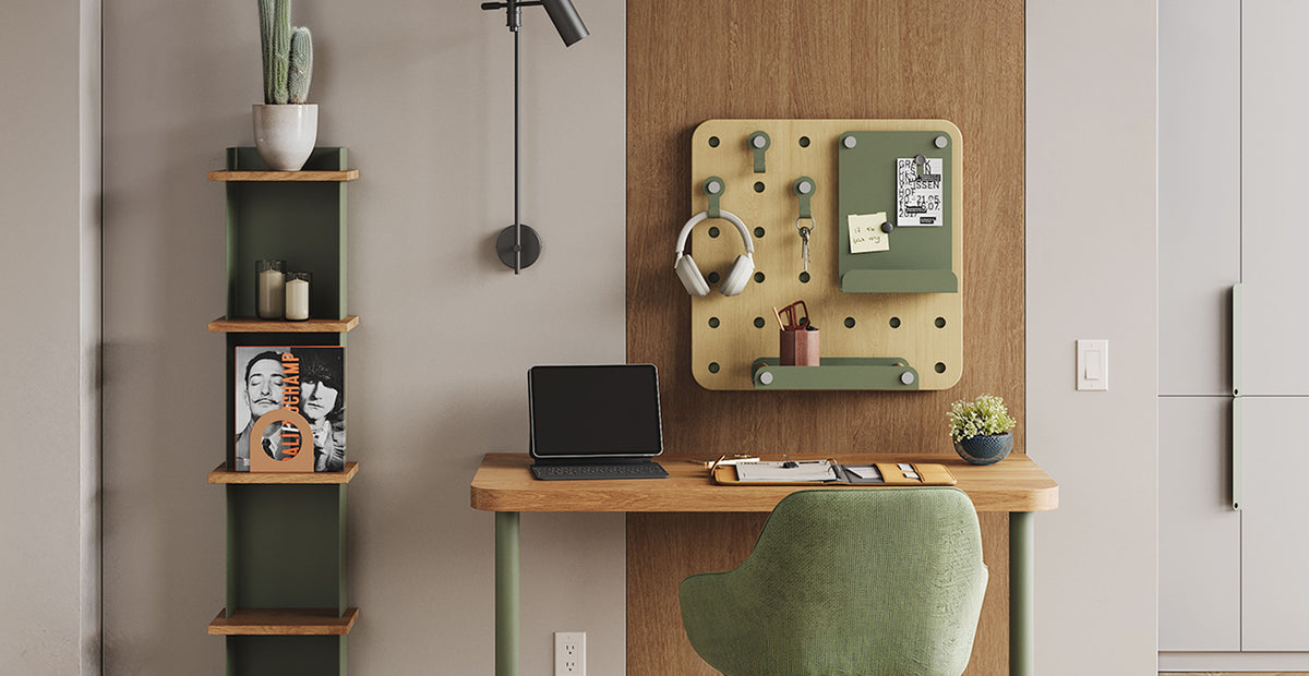 Compact home office with a wood desk laptop pegboard organizer vertical wall shelves and a green upholstered chair