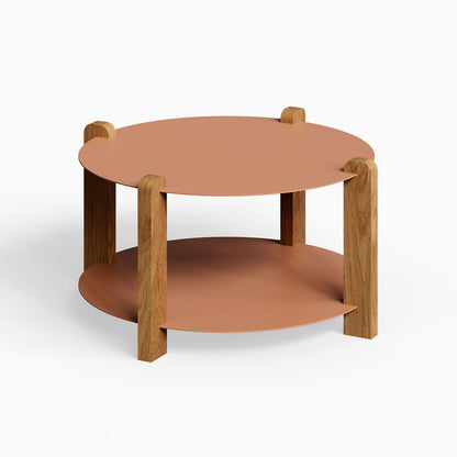 Otis Round Coffee Table featuring a minimalist design with a round clay-colored metal top and shelf supported by solid white oak legs, combining wood and steel for durable, functional style.