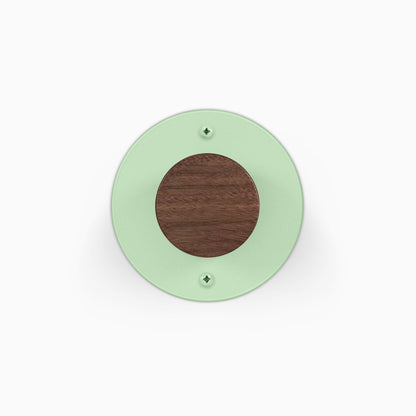 Runda Coat Rack 1 round green wall mounted coat rack with dark wood center and two visible mounting screws