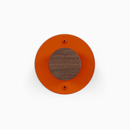 Runda Coat Rack 1 orange circular wall mounted rack with a round wood accent and two visible mounting screws