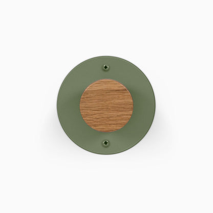 Runda Coat Rack 1 round green wall mounted coat rack with a wood center and two visible mounting screws on a white background