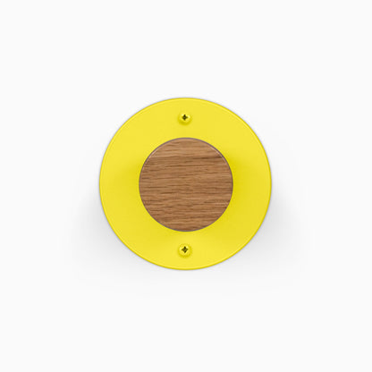 Runda Coat Rack 1 yellow circular wall hook with a solid wood center and two visible mounting screws