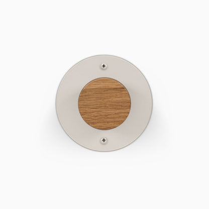 Runda Coat Rack 1 round wall mounted coat rack with a light metal plate wood center and two visible mounting screws