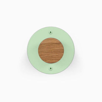 Runda Coat Rack 1 green circular wall mounted coat rack with a natural wood center and two visible mounting screws