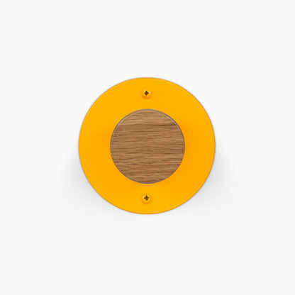 Runda Coat Rack 1 orange circular wall mounted coat rack with a round wood center and two visible mounting screws