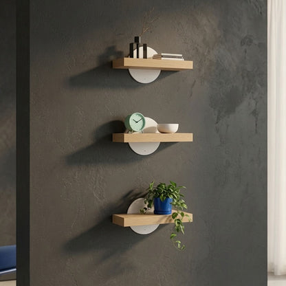 Three Shortie Deux Wall Shelves mounted on a dark textured wall displaying decorative items including books, a clock, a bowl, and a potted plant in a minimalist, functional design that maximizes wall space.