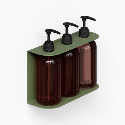 Soap Opera Shower Dispenser wall-mounted unit with three dark amber pump bottles held in a sleek olive green metal bracket designed for bathroom organization.