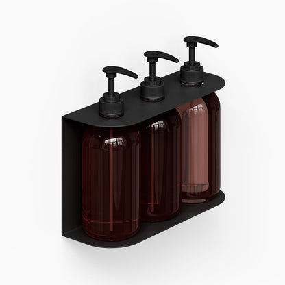 Soap Opera Shower Dispenser mounted on wall with three dark amber bottles and black pump tops in minimalist steel holder for organized bathroom storage.
