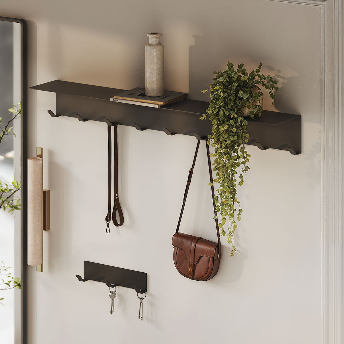 Splendid Shelf + Coat Hooks black wall shelf with integrated hooks holding a handbag keys and leashes with a trailing plant