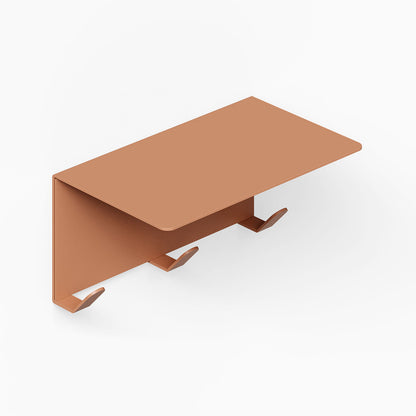 Minimalist rust-resistant metal wall shelf in warm clay tone with three integrated hooks for efficient organization, named Splendid Shelf + Coat Hooks.