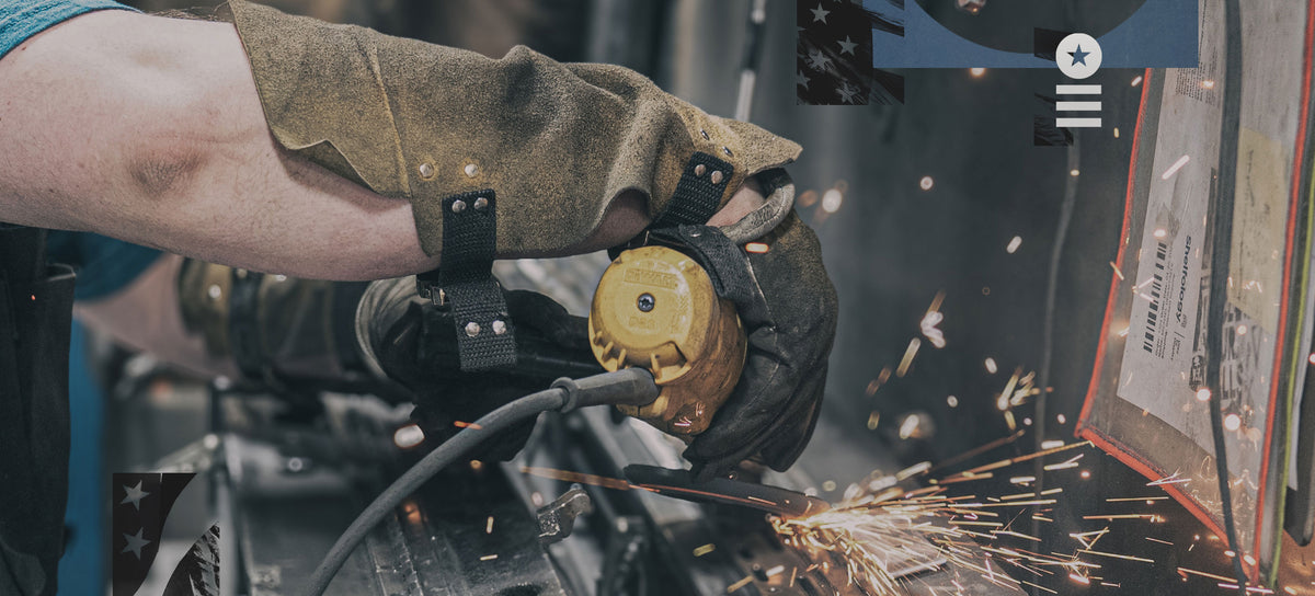 A gloved worker uses an angle grinder to cut metal while bright sparks fly in a workshop setting